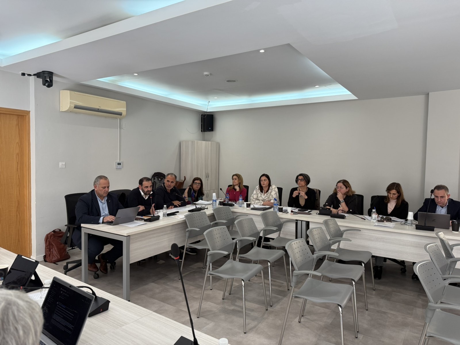 Άτομα που κάθονται σε τραπέζια και παρακολουθούν συνάντηση.